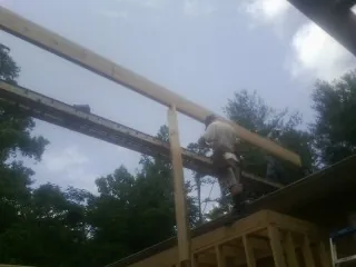 Carpenter setting a ridge beam over a new addition frame — Ice Dam Removal by Roofing Brothers in Lovettsville