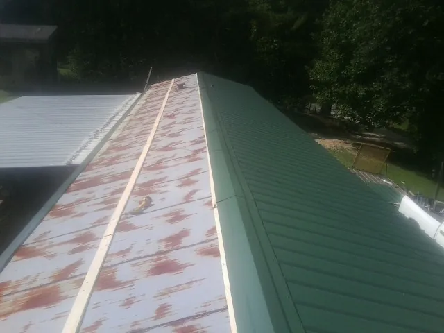 Old rusted panels beside newly installed green metal roofing — Wind Damage Roof Repair by Roofing Brothers in Lovettsville