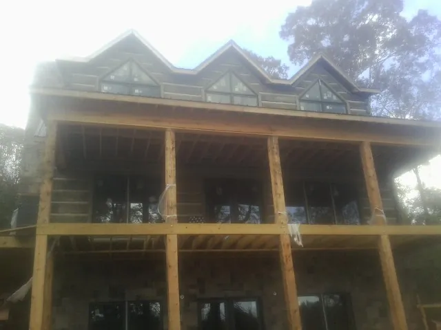 Dormers and porch framing on a large log home under construction — Roof Coating work by our crew in Lovettsville
