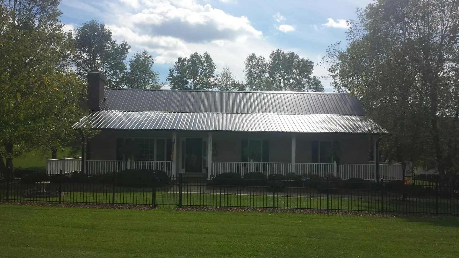 Gray metal roof on a brick ranch with a full width front porch — Gutter Guard Installation work by our crew in Lovettsville