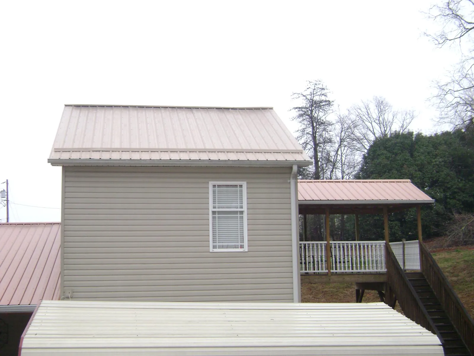 Tan metal roofs on a two story addition and attached porch, from a Roof Replacement job in Lovettsville