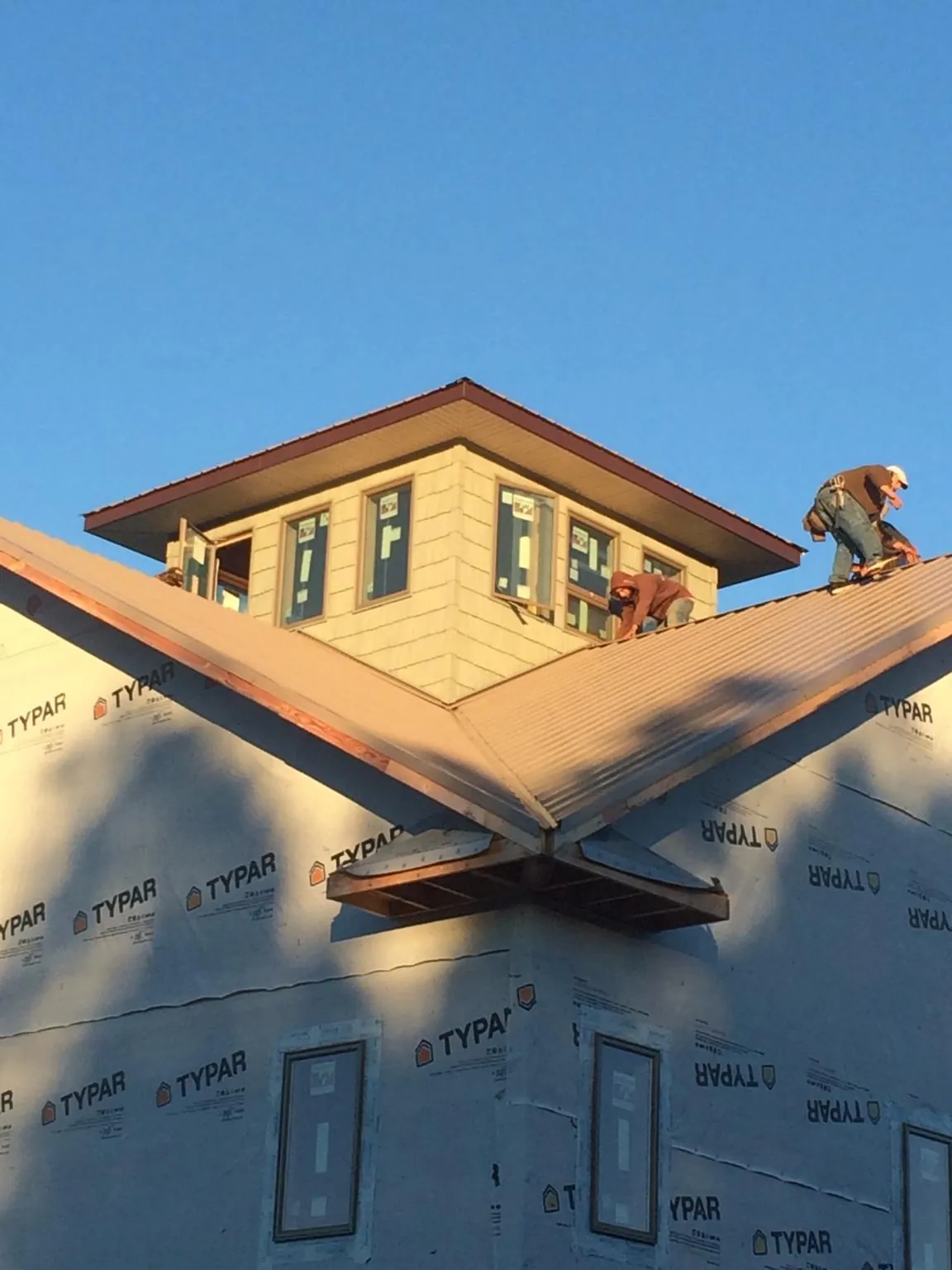 Roofers working around a rooftop cupola on a new metal roof at sunset — Roof Waterproofing in Lovettsville by Roofing Brothers